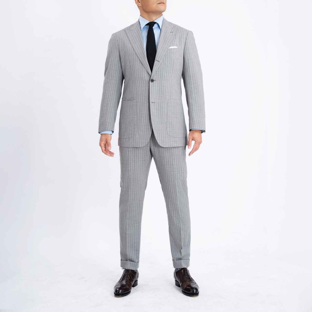 A man in a Florence Suit, Grey pinstripes wool Super 140's, Drago is posing in front of a white background.