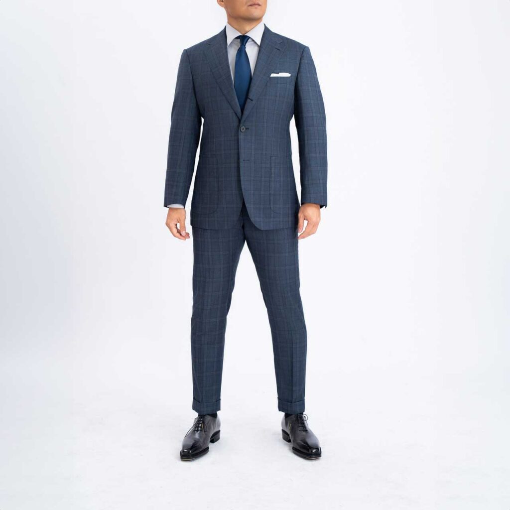 A man in a Blue checkwool Suit, check Wool, Super 150's Loro Piana suit posing for a photo.