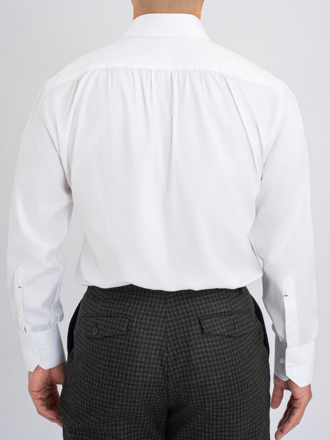 The back view of a man showcasing his elegant Gentlemen's Fashion in a white shirt and black pants.