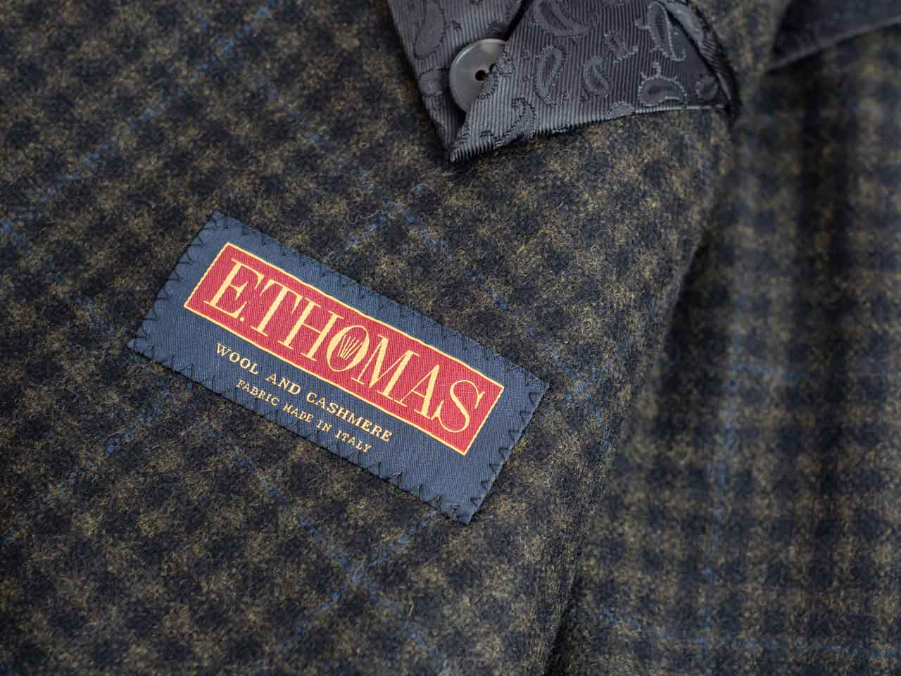 A close up of a label with the word etholas on it, featuring a Light Blue Stripes Suit, Australian Super 150's Wool.