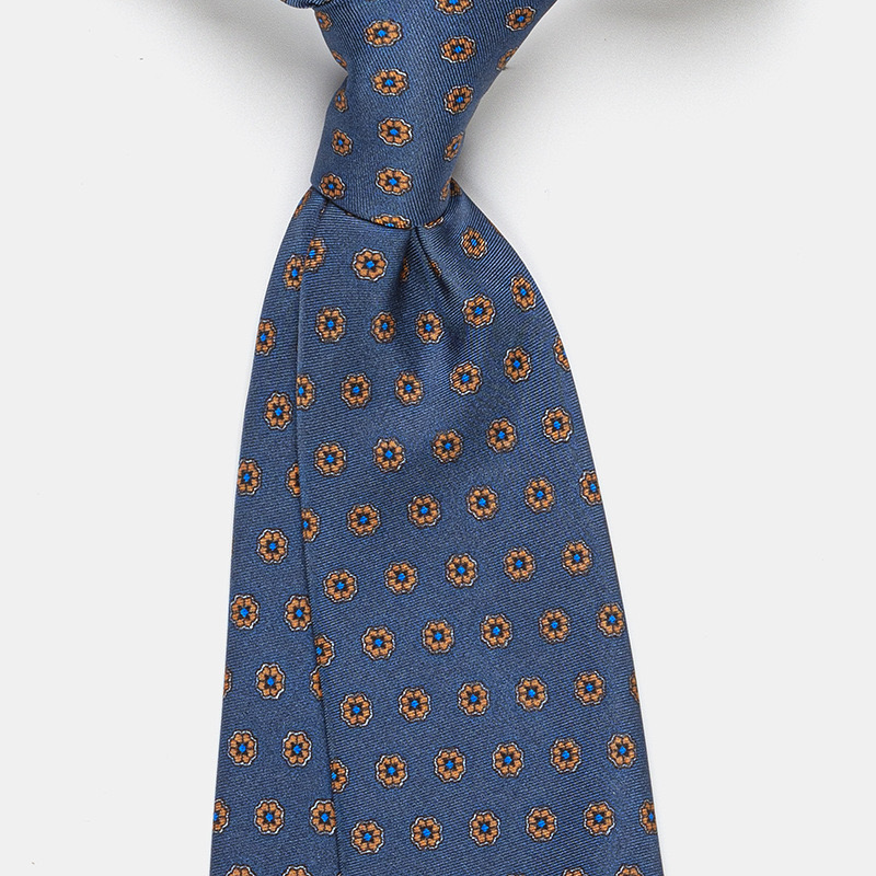 A blue silk tie, n°137 with orange floral patterns worn with a white ceremony shirt.