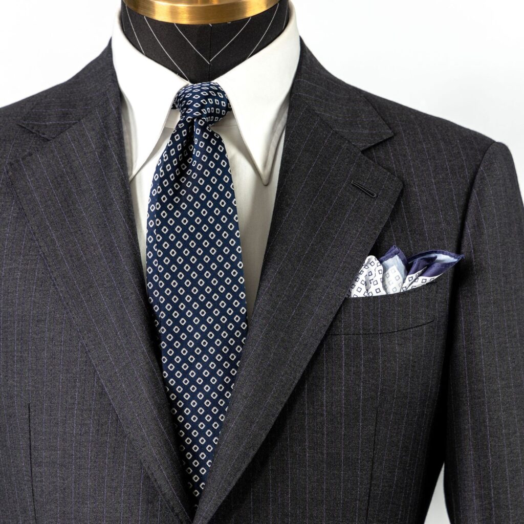 Mannequin displaying a grey pinstripe suit with a patterned tie and pocket square.