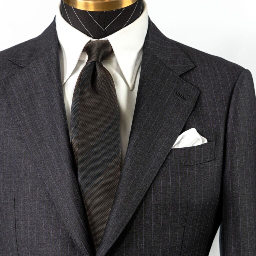 Close-up of a navy pinstripe suit with a tie and pocket square on a mannequin.