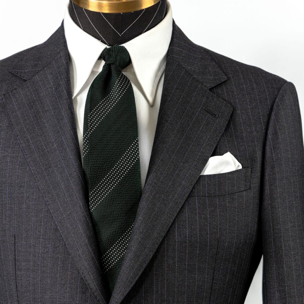 A close-up view of a mannequin dressed in a pinstriped suit with a dark tie and white pocket square.