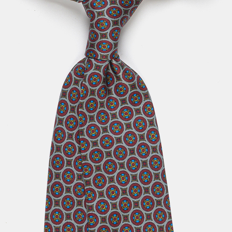 A Silk tie, n°139 gray necktie with a blue and red circular pattern to wear with a white ceremony shirt.