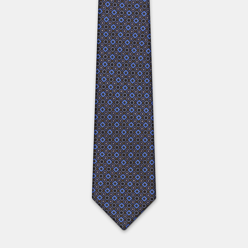 A patterned Silk tie, n°137 with blue and orange design on a white background, perfect for a white ceremony shirt.