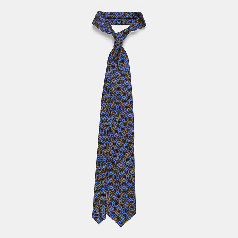 A patterned blue silk tie, n°137 displayed on a white ceremony shirt.