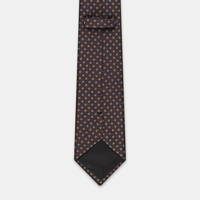 Silk tie, n°137 with a dark background and colorful motifs, displayed on a white ceremony shirt.