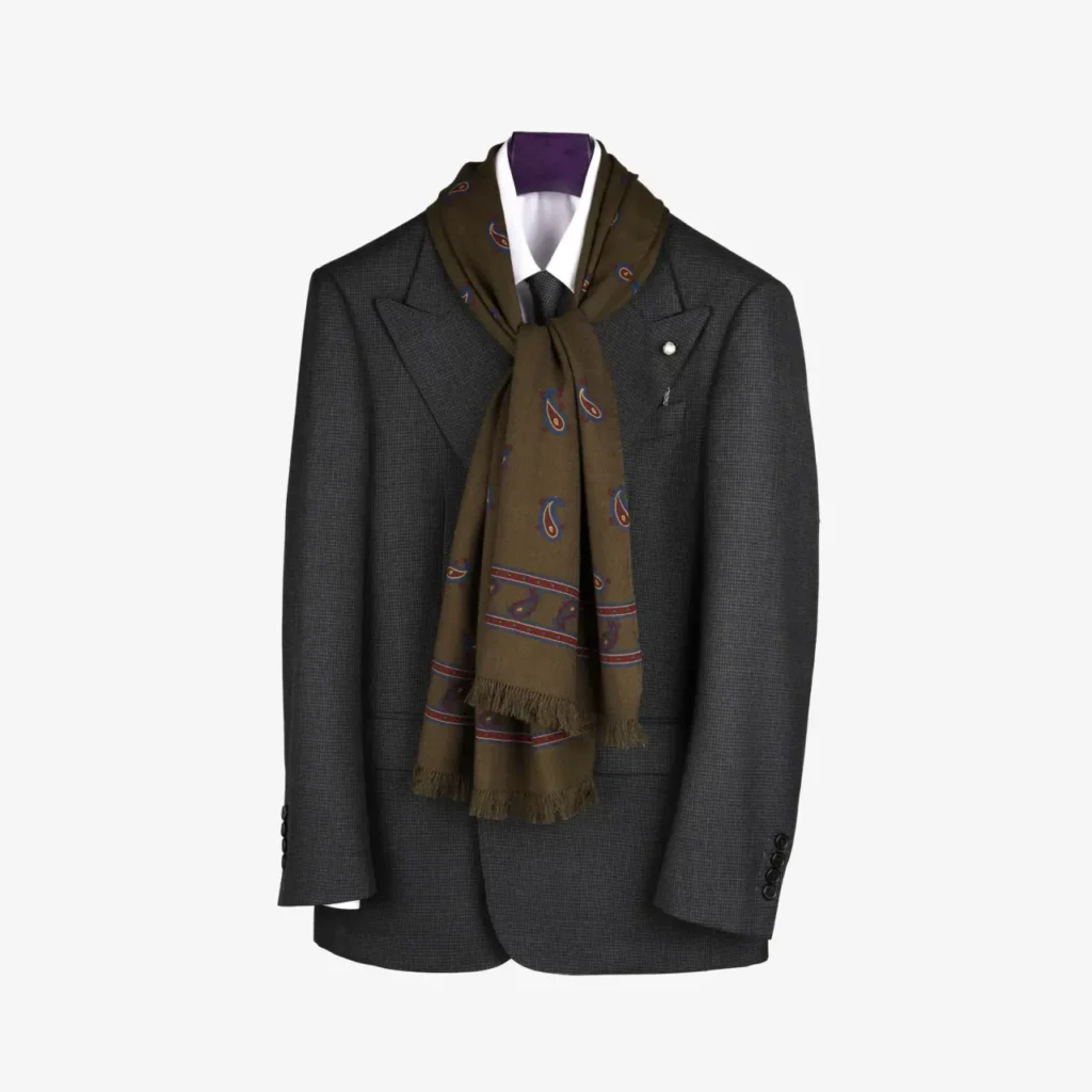 A dark grey suit jacket and white dress shirt on a hanger, elegantly accessorized with the Lunema – Wool and silk scarf in Indigo draped around the collar.