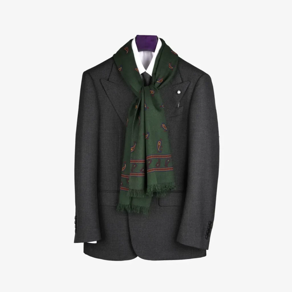A dark gray suit jacket hangs on a plain background, styled with the Lunema wool and silk scarf in Indigo draped around the collar and accented by purple fabric at the neck.