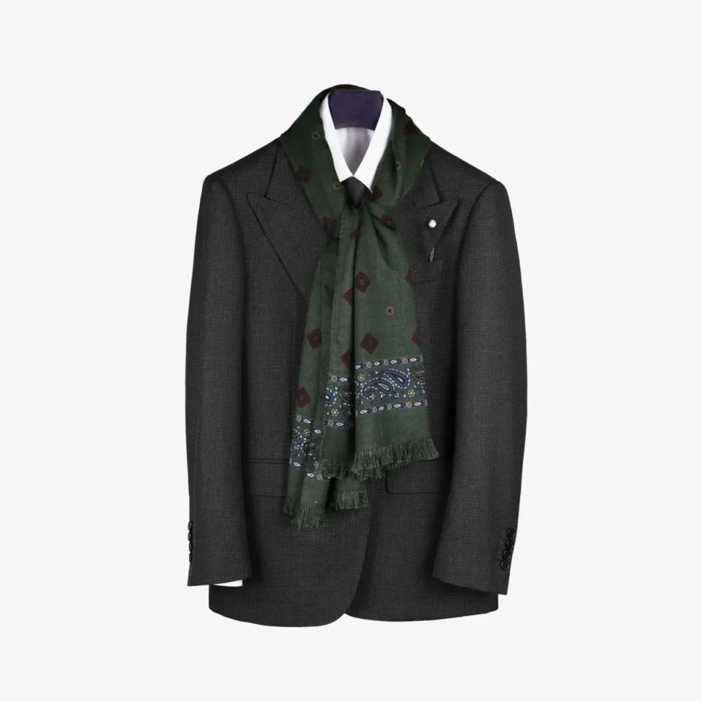 A dark gray suit jacket on a hanger with a white dress shirt, featuring the Kandora – Wool and Silk Scarf in Forest Green elegantly draped around the collar.
