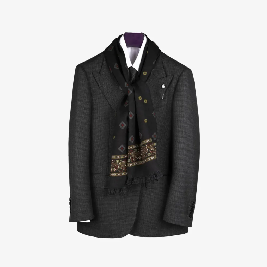 A dark gray suit jacket with a white shirt and the Kandora – Wool and Silk Scarf in Forest Green draped around the collar, displayed on a hanger against a plain background.