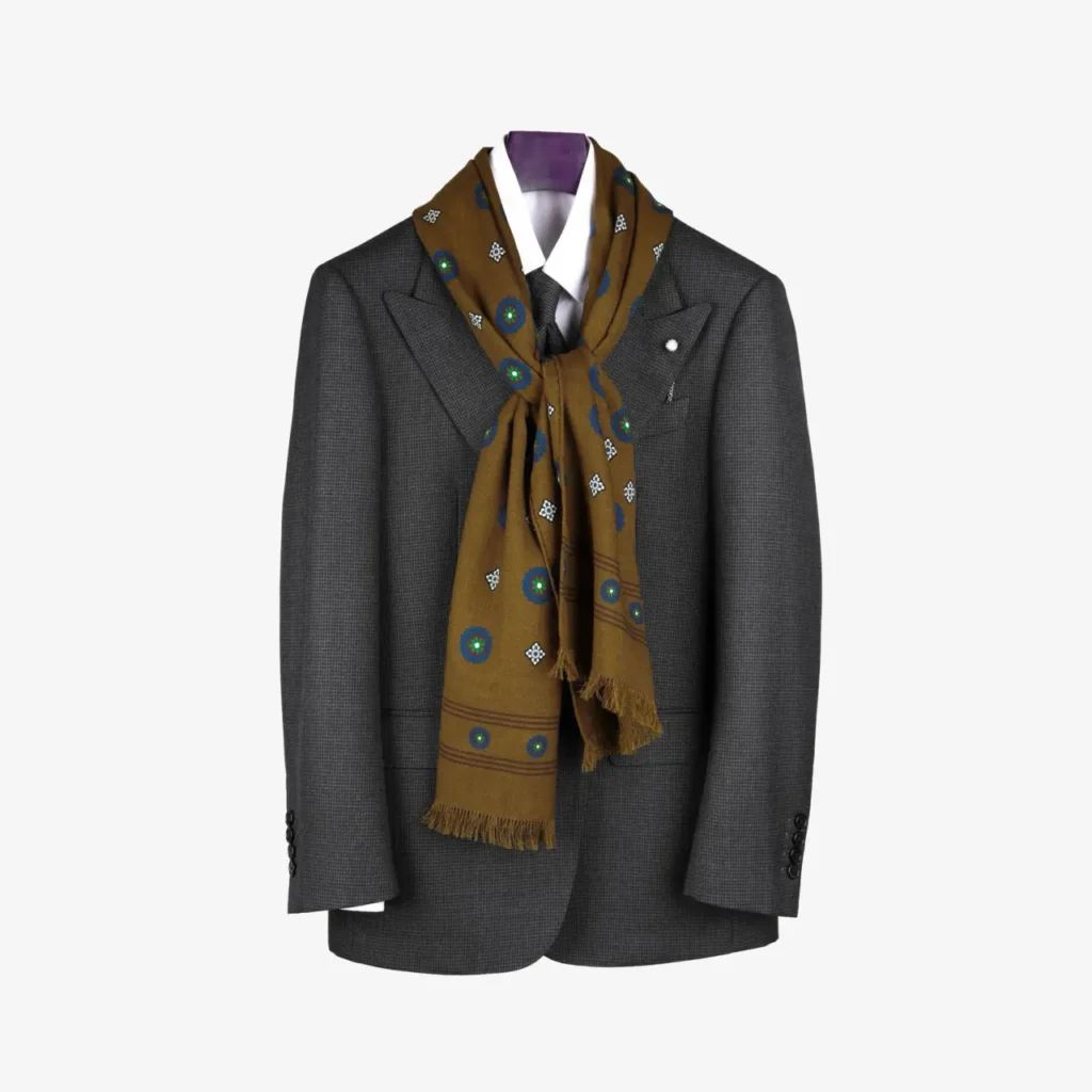 A gray suit jacket with a white shirt and dark tie is complemented by the Lunema – Wool and silk scarf in Midnight blue, draped stylishly around the collar for a refined touch.