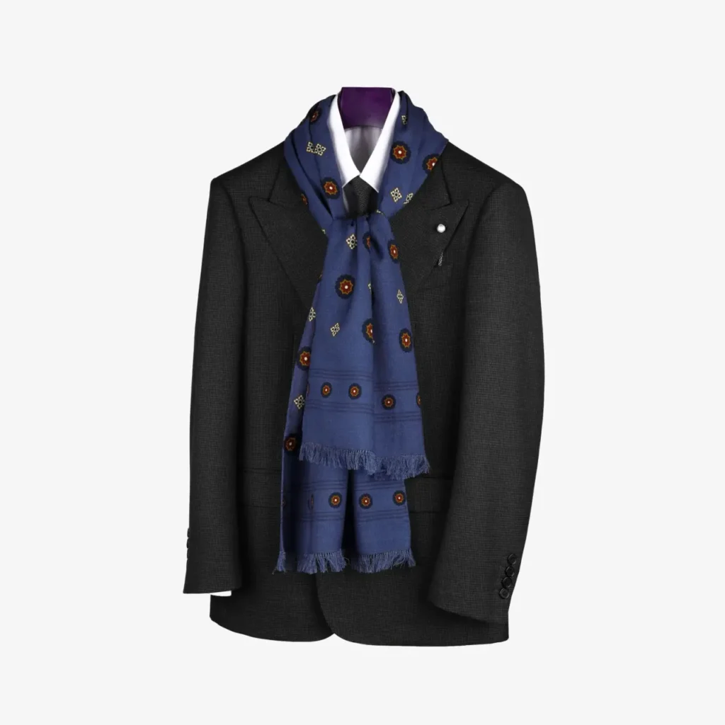 A dark suit jacket on a hanger with a crisp white shirt and the Lunema – Wool and silk scarf, Midnight blue, elegantly draped around the collar adds a touch of sophistication.