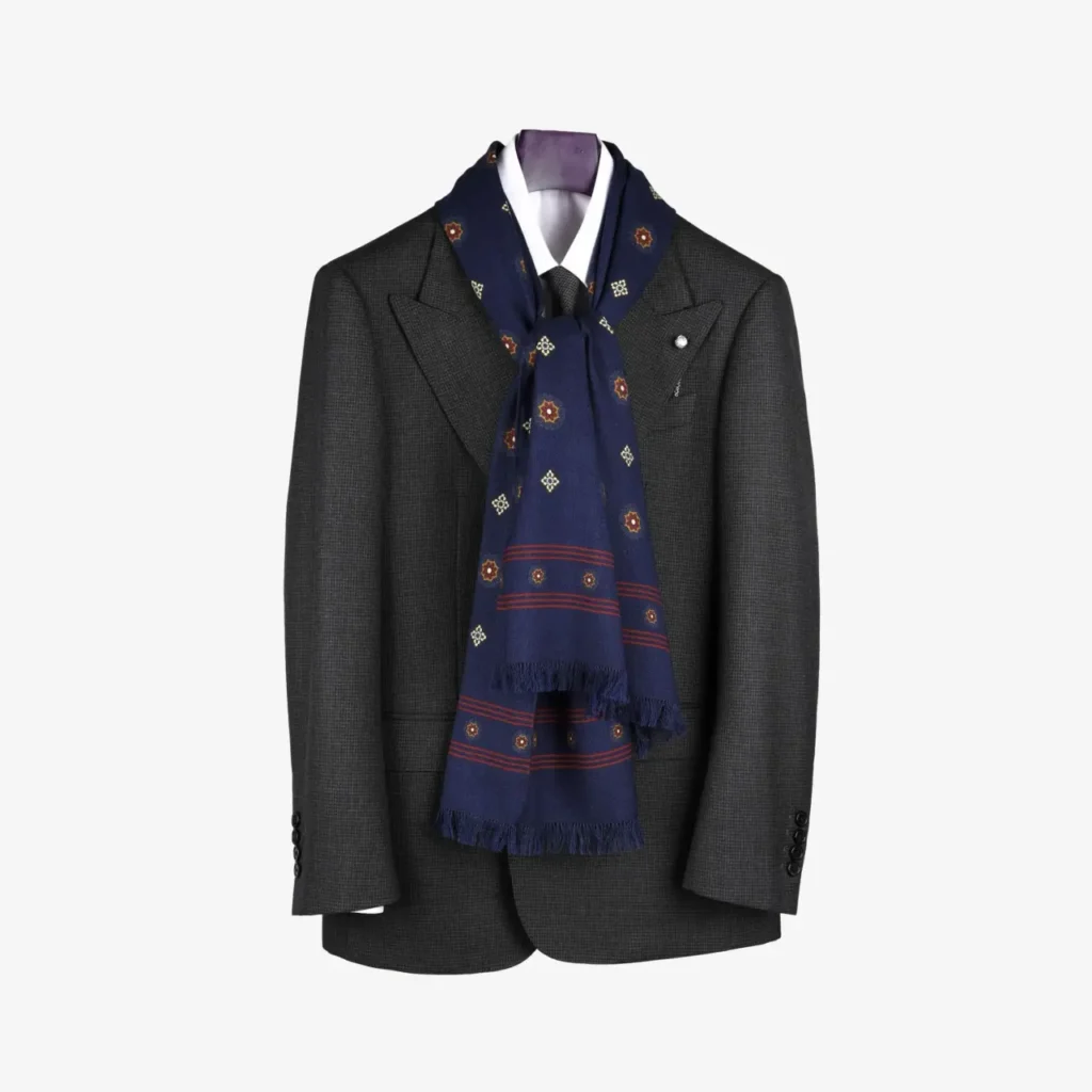 A dark gray suit jacket displayed on a mannequin, paired with a white dress shirt and finished with the Lunema – Wool and silk scarf in Midnight blue draped around the collar for a touch of sophistication.