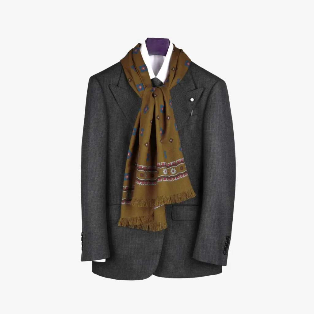 A gray suit jacket displayed on a hanger, elegantly accented with the Voluna – Wool and Silk Scarf in mustard draped around the neck.