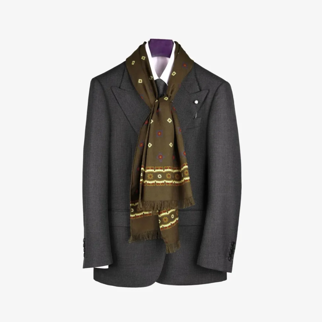 A dark grey suit jacket on a hanger, styled with a white shirt and the Voluna – Wool and Silk Scarf in Olive green draped around the collar.