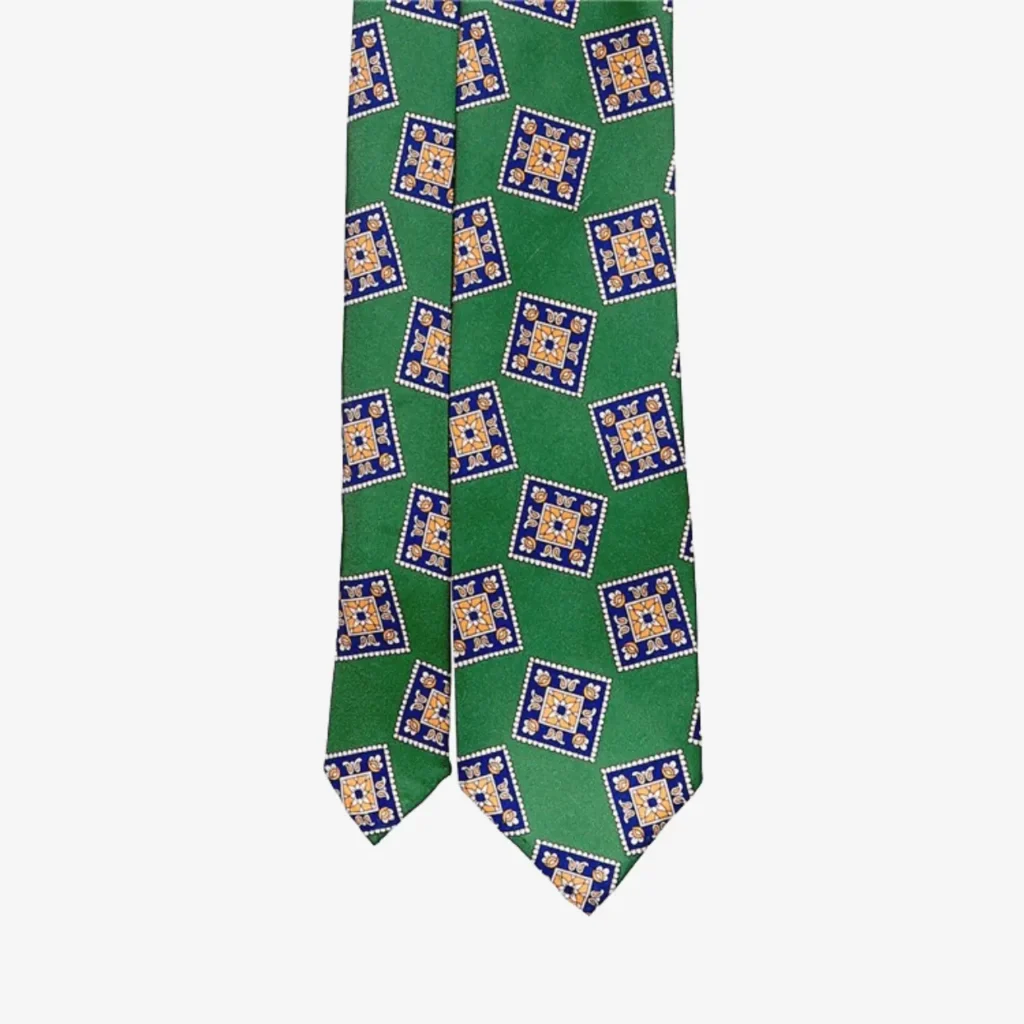 The Blue Striped Silk Tie – Brown (Copy) features modern blue, yellow, and white square patterns on green, adding a contemporary twist to the classic design.