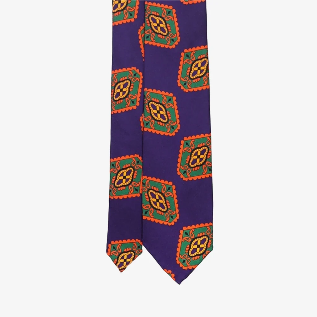The Geometric Floral Silk Tie – Blue features a vibrant pattern of geometric shapes, providing a bold twist on traditional neckwear styles.